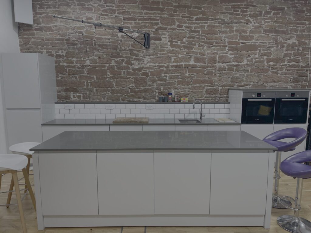 The full kitchen set in Studio One at Lake District Film Studios, with island unit, hob and ovens against the exposed stone wall